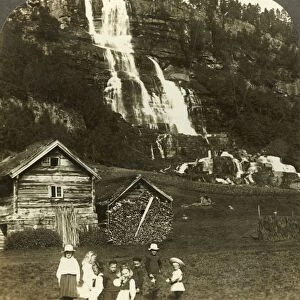 Children at play in a farmers field with terraced Tvinde waterfall, Vossevangen