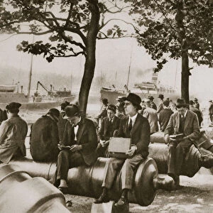 City workers lunching at Tower wharf, seated on old cannons, c1920s-c1930s. Artist