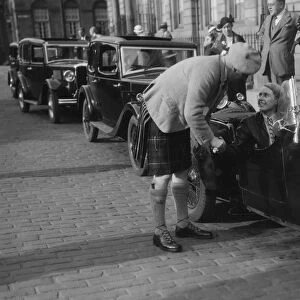 Kitty Brunell in her Aston Martin, chatting to a man in Highland dress, RSAC Scottish Rally, 1933