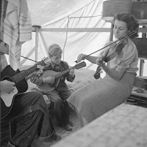 Migrant family from Arkansas playing hill-billy songs, FSA... migratory camp, Calipatria, CA, 1939. Creator: Dorothea Lange