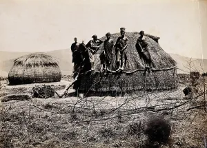 Kraal Prints: Africa: a group of African people standing on a kraal hut