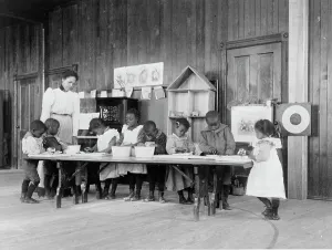 Eight African American children, in kindergarten, learning washing and ironing... 1899 or 1900. Creator: Frances Benjamin Johnston