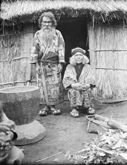 Aino Prints: Ainu man and seated woman at the entrance of a hut, 1908. Creator: Arnold Genthe