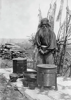 Containers Prints: Ainu man standing outdoors on a mat covered with clay containers