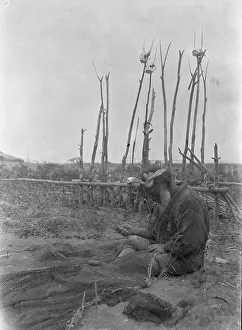 Aino Prints: Ainu seated outside working on nets, 1908. Creator: Arnold Genthe