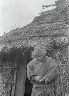Ainu woman outside a hut, 1908. Creator: Arnold Genthe