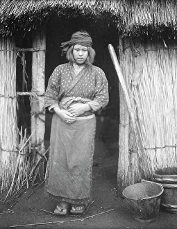 Aino Prints: Ainu woman standing by the doorway of a hut, 1908. Creator: Arnold Genthe