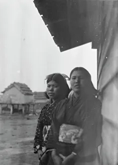 Stilts Prints: Two Ainu women standing outside by the wall of a wooden hut, 1908. Creator: Arnold Genthe