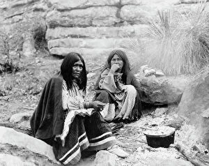 Fire Collection: Two Apache Indian women at campfire, cooking pot in front of one, c1903