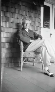 Wicker Chair Prints: Arnold Genthe seated in a chair on a porch, between 1911 and 1942. Creator: Arnold Genthe