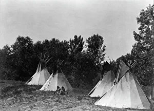 An Assiniboin camp containing four tepees with Indians seated on ground, c1908. Creator: Edward Sheriff Curtis