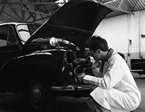 Motor Maintenance Gallery: Auto electrician changing a light bulb on a Morris Minor, Nottingham, Nottinghamshire, 1961