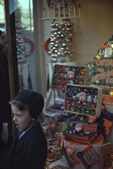 Boy beside store window display of Christmas ornaments, between 1941 and 1942. Creator: Unknown