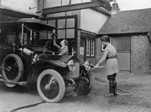 Chauffeuse washing car with hosepipe circa 1911. Creator: Unknown