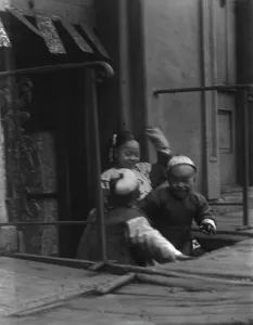 Three children in front of a cellar door, Chinatown, San Francisco, between 1896 and 1906. Creator: Arnold Genthe