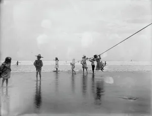 Young Girl Prints: Children swinging on pier rope at beach, between 1900 and 1910. Creator: Unknown
