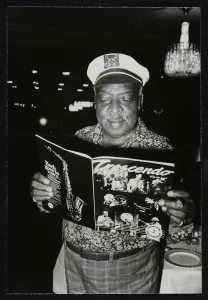 Count Basie Gallery: Count Basie reading a copy of Crescendo magazine at the Grosvenor House Hotel, London, 1979