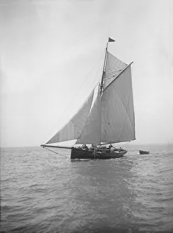 The cutter Citara under sail and towing tender, 1911. Creator: Kirk & Sons of Cowes