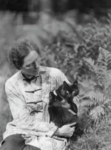 Egger, Gabrielle, Miss, friend of, with cat, seated outdoors, between 1926 and 1930. Creator: Arnold Genthe