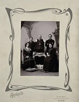 Disability Prints: A family portrait: a man without arms and legs poses on a table surrounded by family