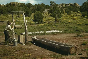 Milk Churn Prints: Faro Caudill drawing water from his well, Pie Town, New Mexico, 1940. Creator: Russell Lee