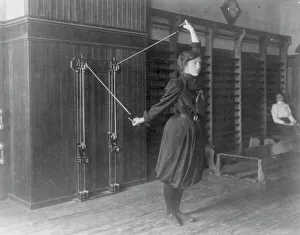 Gymnasium Prints: Female student exercising with a wall-mounted device using ropes