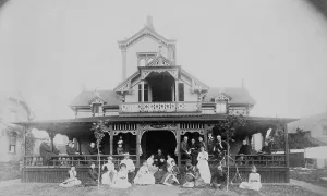 Frances Benjamin Johnston and family on porch and in front of house, between 1890 and 1910. Creator: Unknown