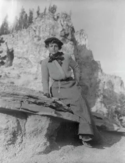 Frances Benjamin Johnston, full-length portrait, sitting on ledge with... between 1888 and 1920. Creator: Frances Benjamin Johnston