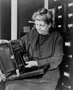Frances Benjamin Johnston, three-quarter length portrait, holding and looking down... c1950. Creator: Unknown