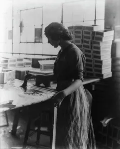 Glue Prints: Girl painting strips with glue to assemble cigar boxes