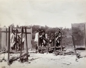 Mumbai Maharashtra India Prints: A group of men lower the body of a dead man on to a pyre of logs prior to a Hindu