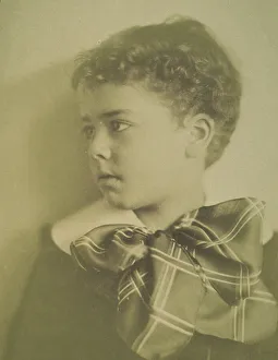 Head-and-shoulders portrait of a young boy with a large plaid bow at the neck of his... c1900. Creator: Horace L Bundy