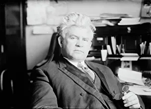 House Of Representatives Prints: H.T. Rainey, holding bifocals, at desk, 1911. Creator: Bain News Service