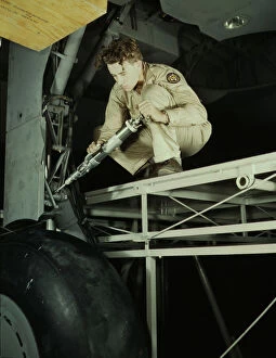 Aeronautics Gallery: A hydraulic mechanic greasing the landing gear of a transport... Fort Worth, Texas, 1942