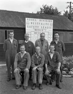 Overalls Prints: ICI powder works team in front of the Safety League board