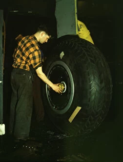 Inspecting of landing wheel of the transport planes at Willow Run, between 1941 and 1945. Creator: Howard Hollem