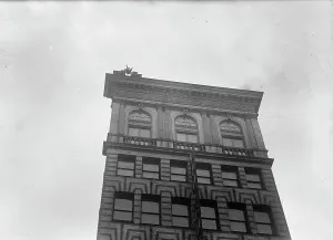 Publicity Stunt Prints: J. Reynolds, Performing Acrobatic And Balancing Acts On High Cornice Above 9th Street