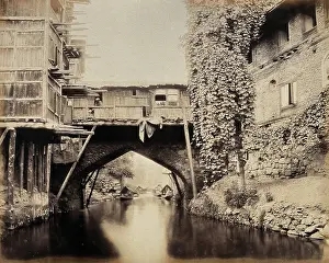 South Asian Prints: Kashmir: a built-over bridge on a canal betweeen houses, c1870s. Creator: Samuel Bourne