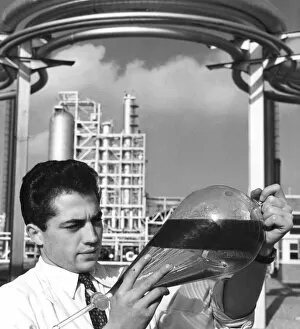 A laboratory worker holds a separating funnel of oil, Dunkirk refinery, France, 1950s
