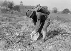 Shovel Prints: Leonard D. Mahon with steel helmet he invented that could be used as shovel