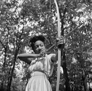 Aiming Collection: Loretta Gyles pulling a bow at Camp Fern Rock, Bear Mountain, New York, 1943 Creator: Gordon Parks