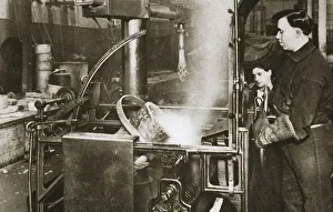 Metal Industry Prints: Making money; lowering a pot of liquid metal into a machine, 20th century. Artist