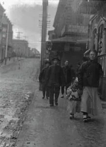 Chinese American Prints: Man and a boy walking down a sidewalk with other people