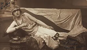 Cross Dressing Prints: A man in drag poses wearing delicate attire; curled up on a piece of furniture