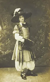 A man in drag wearing a very large hat with a veil, stands in front of a painted... 1911. Creator: Unknown