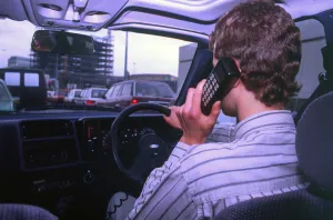 Man driving whilst using built-in car telephone 1990. Creator: Unknown Man driving whilst using built-in car telephone 1990. Creator: Unknown