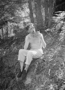 Horns Prints: Man playing panpipes in the woods, between 1911 and 1942. Creator: Arnold Genthe