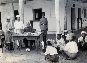 Burma Prints: A man sitting at a table examining passports