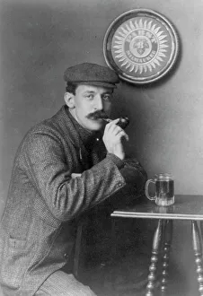 Man at table with pipe and mug under Pabst - Milwaukee sign - C.C. Jones, between c1890 and c1910. Creator: Frances Benjamin Johnston. Man at table with pipe and mug under Pabst - Milwaukee sign - C.C. Jones, between c1890 and c1910