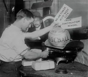 Weighing Prints: Medicine ball being weighed by Post Office employee; shipping tags read: Mr